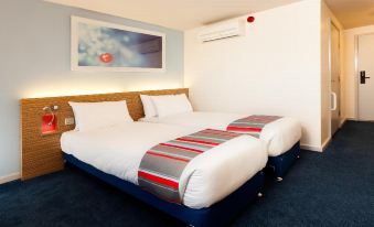 a hotel room with two beds , a blue carpet , and a painting on the wall at Travelodge Ashbourne