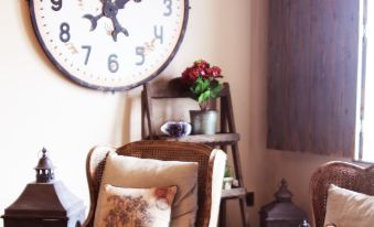 a living room with a large clock on the wall , two chairs , and a potted plant at Maison