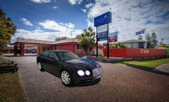 a black bentley continental gtc , a luxury car parked in front of a hotel building at Lake Macquarie Motor Inn
