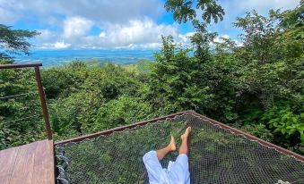 a person is relaxing in a hammock on a wooden deck with a beautiful view of the ocean at Domos Mirador Romantic Private Honeymoon Glamping