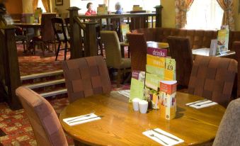 a restaurant with wooden tables and chairs , and several people seated at the tables enjoying their meals at Premier Inn Hull West