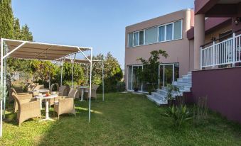 a modern house surrounded by a lush green lawn , with several chairs and umbrellas placed around the property at Sofi