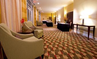 a large , well - lit room with multiple couches and chairs arranged in various positions , creating a comfortable seating area at Holiday Inn Statesboro-University Area