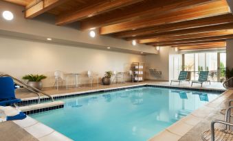 an indoor swimming pool with a wooden ceiling , surrounded by lounge chairs and tables , providing a relaxing atmosphere at Home2 Suites by Hilton Milwaukee Brookfield