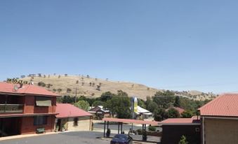 a parking lot with cars parked in front of a building , and a mountain in the background at Poet's Recall Motel