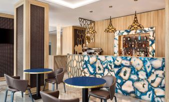 a modern bar area with blue and white marble walls , gold accents , and various dining furniture at Ramada by Wyndham Ramnicu Valcea