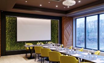 a conference room with yellow chairs and tables , a large screen , and green walls , ready for meetings or events at Hotel Victory