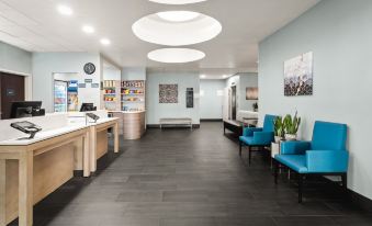 a modern hotel lobby with blue walls , wooden furniture , and circular light fixtures , as well as a dining area with chairs and tables at Holiday Inn & Suites Bothell