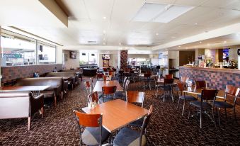 a large , well - lit restaurant with multiple dining tables and chairs , as well as a bar area at Prince of Wales Hotel