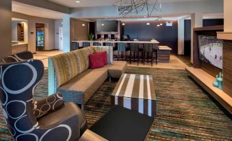 a hotel lobby with a large couch , bar stools , and a television mounted on the wall at Residence Inn Boston Bridgewater