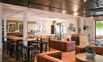 a modern restaurant with wooden floors and white walls , featuring a bar area and multiple dining tables at Margarets Beach Resort