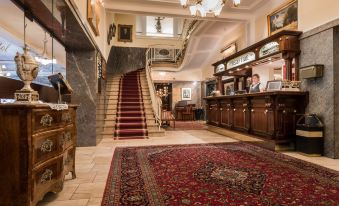 a grand foyer with a red carpet and a staircase leading to the second floor at Bellevue Rheinhotel