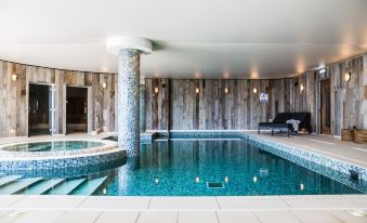 a large indoor pool surrounded by wooden walls , with a hot tub in the background at Gara Rock