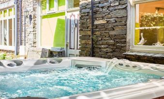 a hot tub with jets is surrounded by a stone wall and has a glass door leading into a room at Lakeside Cottage