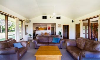 a spacious living room with multiple couches and chairs arranged around a coffee table , creating a cozy atmosphere at Stay in Mudgee