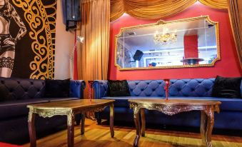 a cozy living room with blue couches , wooden coffee tables , and a large mirror on the wall at Lux Hotel