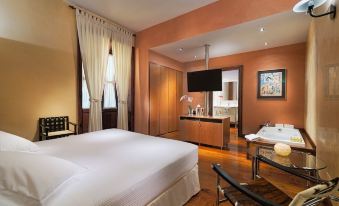 a large bedroom with a king - sized bed , a flat - screen tv mounted on the wall , and a bathroom in the background at Hotel San Roque