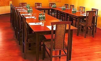 a long dining table set up for a meeting , with several chairs arranged around it at Hotel Bella