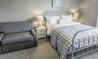 a cozy bedroom with a grey bed , a couch , and a chair , all decorated in a neutral color scheme at The Saracens Head