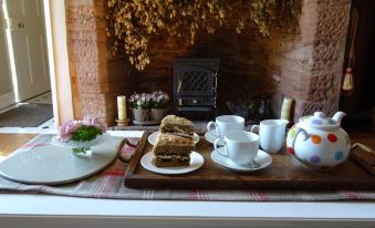 a tray with a variety of food items and a teapot placed on a table in front of a fireplace at Moor Court Farm