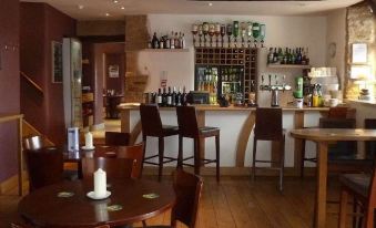 a bar with several chairs and tables , as well as a wine rack filled with bottles at Cartwright Hotel