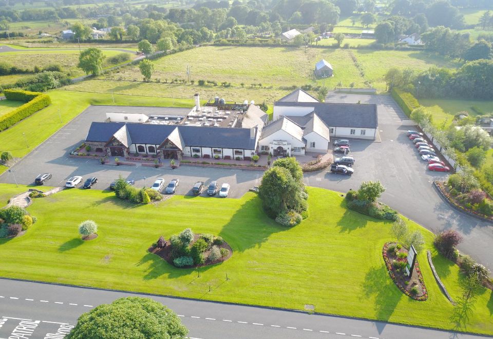 an aerial view of a large building with multiple parking spaces and green fields surrounding it at Ballymac Hotel