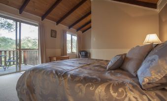 a spacious bedroom with a large bed and two windows , one on the left and one on the right at William Bay Cottages