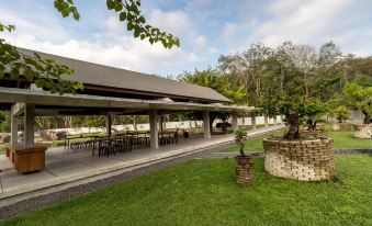 a large outdoor dining area with tables and chairs , surrounded by trees and a grassy area at Berugo Cottage