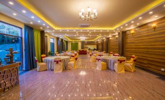 a large , well - lit banquet hall with multiple dining tables and chairs arranged for a formal event at Aagantuk Resort
