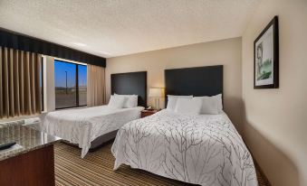 a hotel room with two beds , each made up with white sheets and black headboards , next to a window at Best Western Park Oasis Inn