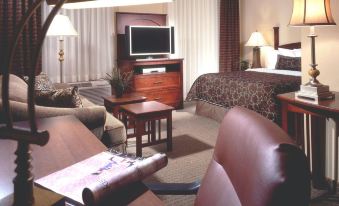 a modern hotel room with a large bed , leather couches , and wooden tables , as well as a flat - screen tv at Staybridge Suites Buffalo