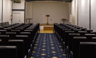 a large conference room with rows of black chairs and a blue and white patterned carpet at Eastcoaster Tasmania
