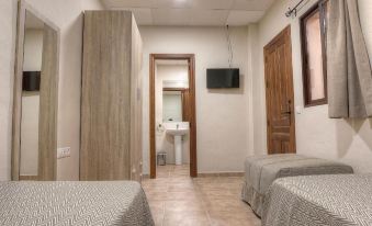 a clean and well - lit room with two beds , a tv , and a bathroom visible through an open door at La Torre
