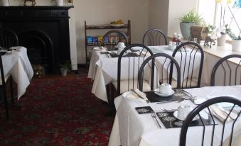 a dining room with tables and chairs set up for a meal , along with a fireplace in the background at Lamb Inn Ringwood Limited