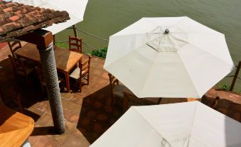 a terrace with multiple white umbrellas , wooden tables , and chairs , offering a view of the water at Casa del Rio
