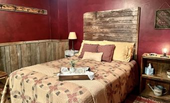 a cozy bedroom with a wooden bed , red walls , and a tray on the bed at Amish Country Comfort