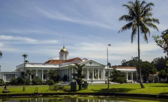 a large white building with a gold dome is surrounded by greenery and water , with palm trees in the background at Applewood B&B