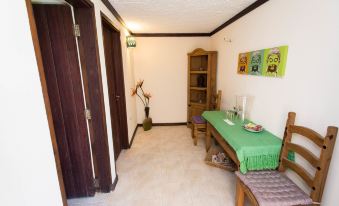 a room with a green table , wooden doors , and a bed , along with a plant and a chair at Santosha Barbados