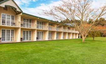 a large , multi - story building with balconies and a green lawn in front of it under a blue sky at Wairakei Resort Taupo