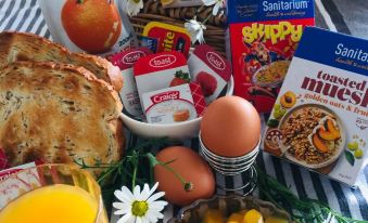 a table is filled with a variety of breakfast items , including eggs , oranges , and bread at Cedar Lodge Motel