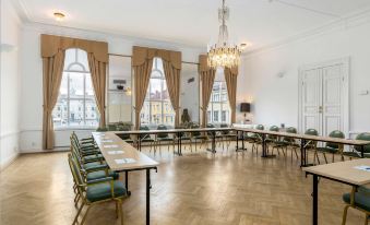 a large , empty room with multiple rows of tables and chairs set up for meetings or events at Vimmerby Stadshotell, WorldHotels Crafted