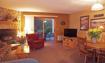 a cozy living room with a couch , chairs , and a television mounted on the wall at Sugar Lake Lodge