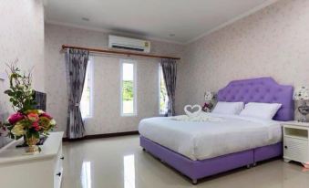 a large bedroom with a white bed and purple headboard , gray curtains , and a purple couch at Belleville Hotel