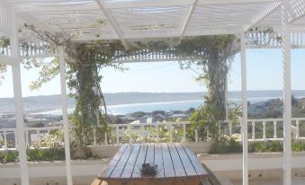 a wooden table under a pergola with a view of the ocean and mountains in the background at Charlotte House