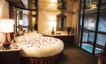 a large bed with red rose petals on it in a room with a mirror and a table at Pocono Palace Resort