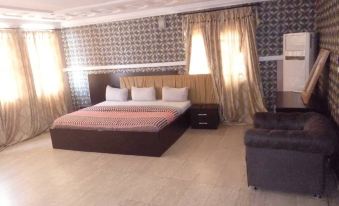 a modern bedroom with a large bed , curtains , and a tv , all under a patterned wall at Brentwood Hotel