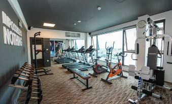 a well - equipped gym with various exercise equipment , including treadmills and weight machines , as well as a large window offering a view of the at Purple Lotus Hotel