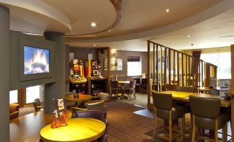 a restaurant with a dining table and chairs , as well as a bar area with a variety of games and entertainment options at Premier Inn Burgess Hill