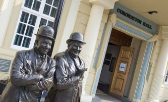 a bronze statue of two men in suits and hats stands in front of a building at Premier Inn Ulverston