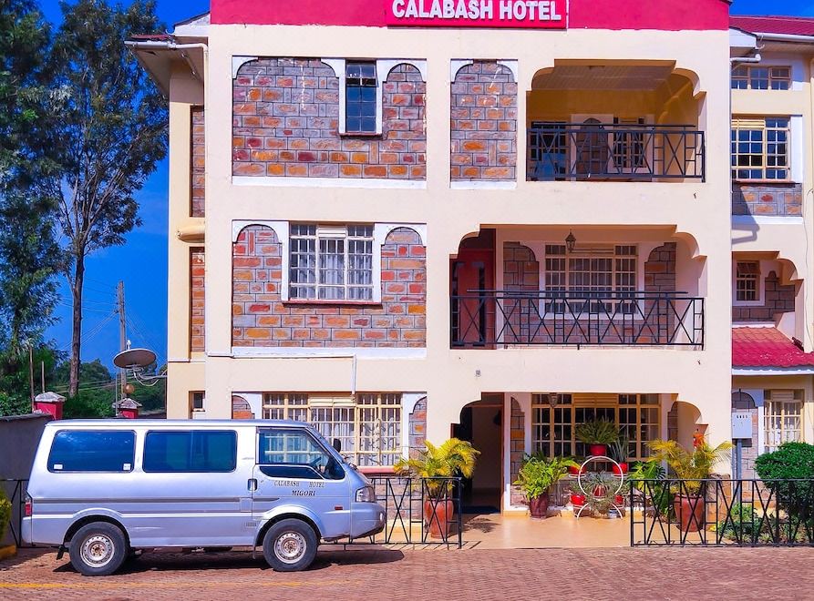 "a red and white building with a sign that says "" calabash hotel "" is next to a car" at Calabash Hotel